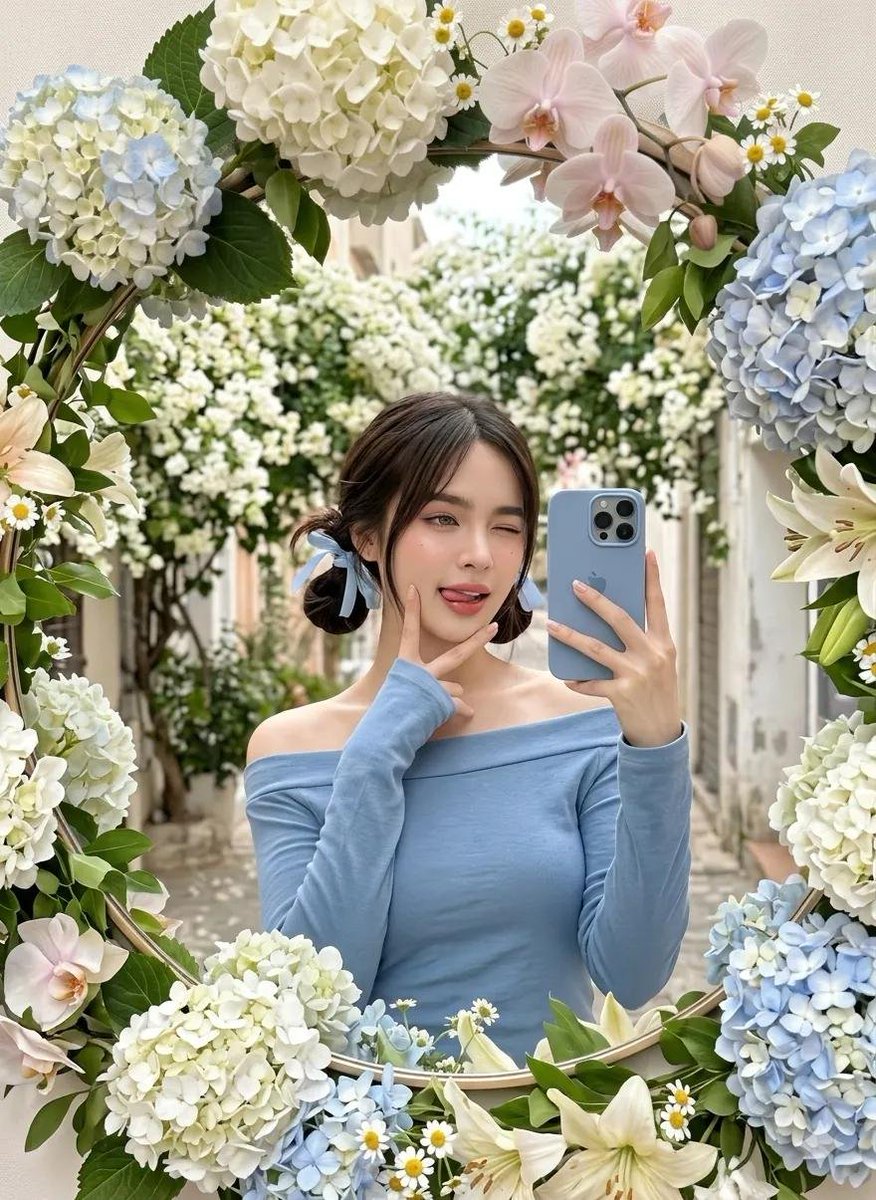 一位可爱的年轻女性在户外拍摄镜面自拍，被装饰华丽的圆形镜子所环绕，镜子上覆盖着茂盛的柔和粉彩色花朵（绣球花、雏菊、百合和兰花）。她妆容柔和自然，皮肤白皙，深棕色头发扎成低低的双髻，系着浅蓝色丝...