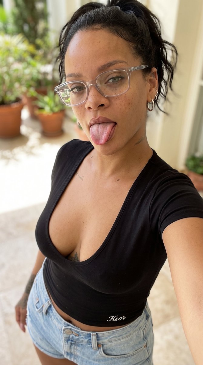 垂直特写自拍，迷人的凯莉·詹娜（Kylie Jenner），黑发俏皮地伸出舌头，穿着橙色低胸上衣和牛仔短裤，面部可见雀斑，戴着眼镜，橙色上衣下摆处绣有精致小巧的白色'Keor'字样，柔和自然光...