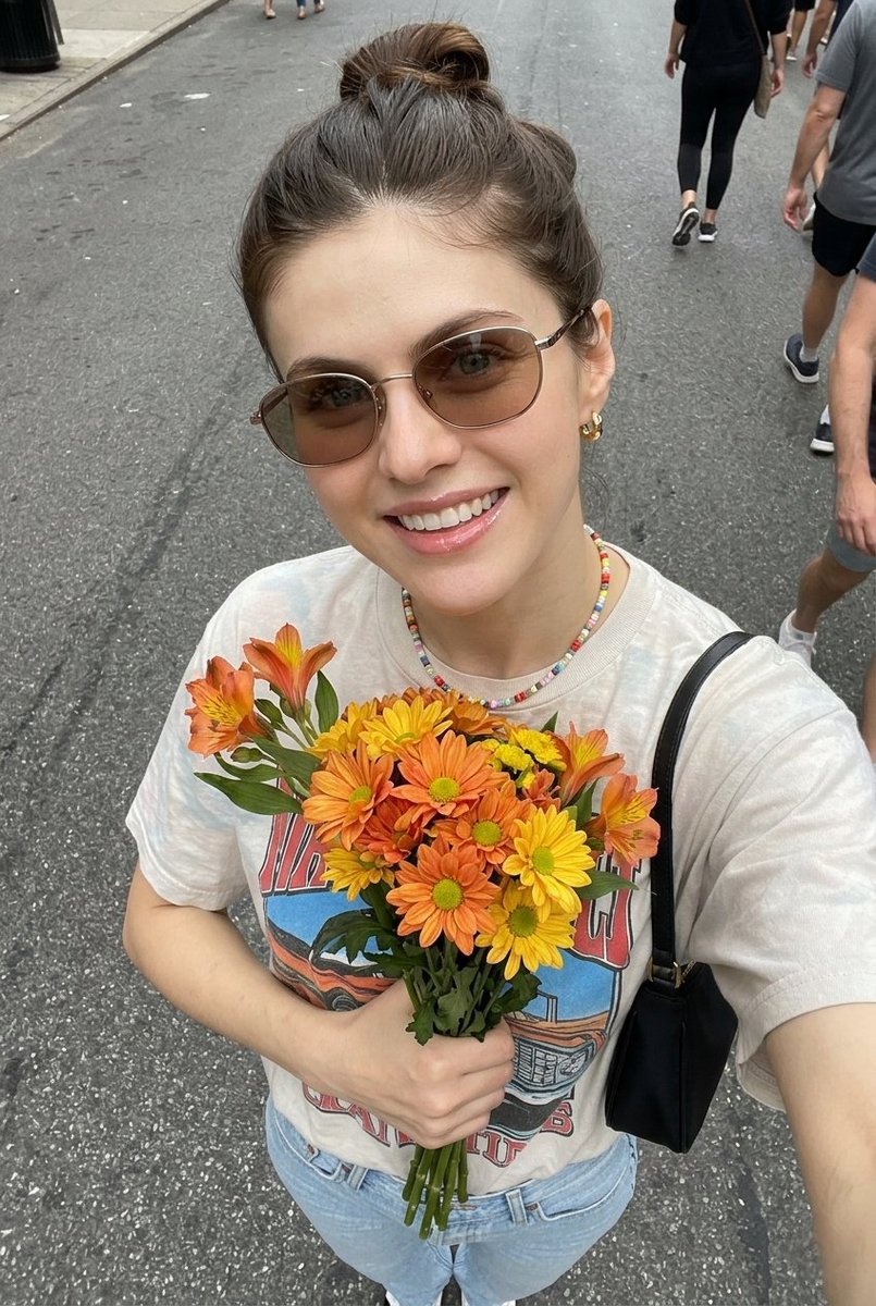 超现实自拍照片，一位年轻女子手持一束新鲜花束， 姿势：俯拍自拍角度，将花束贴近胸前，浅浅微笑，自然放松的表情， 外观：肌肤洁净有光泽，头发整齐地盘成发髻，柔和自然妆容，唇部水润亮泽， 服装：休...