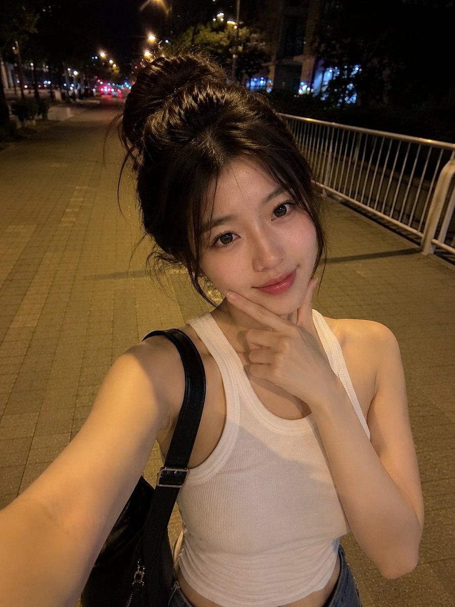 夜晚，一位美丽的东亚年轻女性在安静的城市人行道上户外行走的真实感智能手机自拍。她拥有瓷白肤色、闪亮的大眼睛呈深棕色、小巧笔挺的鼻梁、自然有光泽的粉嫩双唇，以及精致年轻的面部特征。她的深棕色头发...