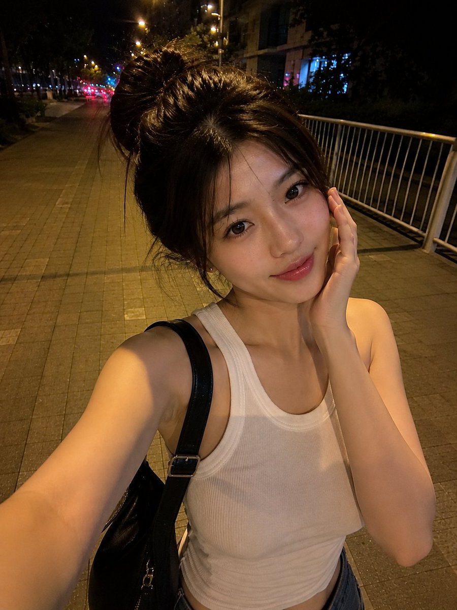 夜晚，一位美丽的东亚年轻女性在安静的城市人行道上户外行走的真实感智能手机自拍。她拥有瓷白肤色、闪亮的大眼睛呈深棕色、小巧笔挺的鼻梁、自然有光泽的粉嫩双唇，以及精致年轻的面部特征。她的深棕色头发...