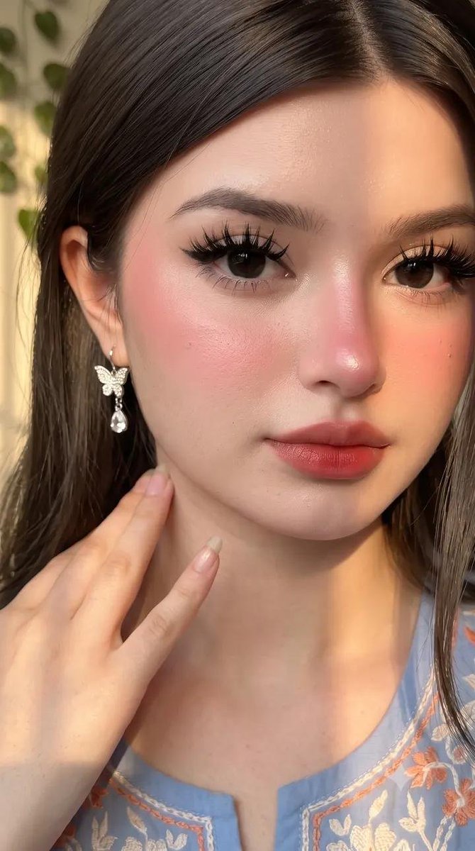 请原样保留她原有的面部特征。她天生容貌美丽，面部对称性完美。她应显得年轻且有女性魅力，拥有自然丰满的胸部，而非平坦的胸部。 这是一张室内特写自拍照，照片中是一位年轻女性，面容柔和甜美，由温暖的...