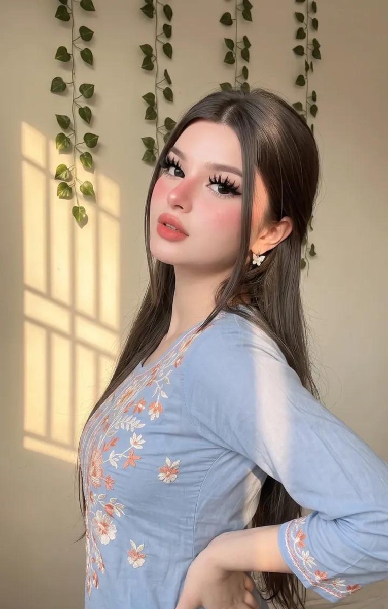 请原样保留她原有的面部特征。她天生容貌美丽，面部对称性完美。她应显得年轻且有女性魅力，拥有自然丰满的胸部，而非平坦的胸部。 这是一张室内特写自拍照，照片中是一位年轻女性，面容柔和甜美，由温暖的...
