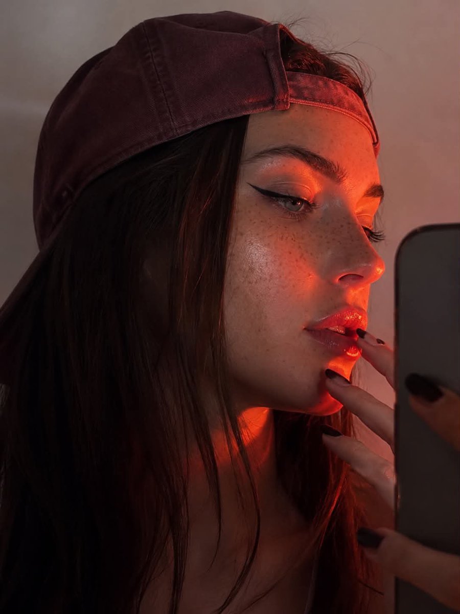不要改变你的特征 3:4 长宽比 一张年轻女性的特写肖像，呈现锐利的侧面轮廓，背景为浅色、中性色调。她戴着一顶稍微偏大的浅酒红色棒球帽，帽子反戴，帽檐向上翘起。戏剧化的强烈红橙色轮廓光照亮她脸...