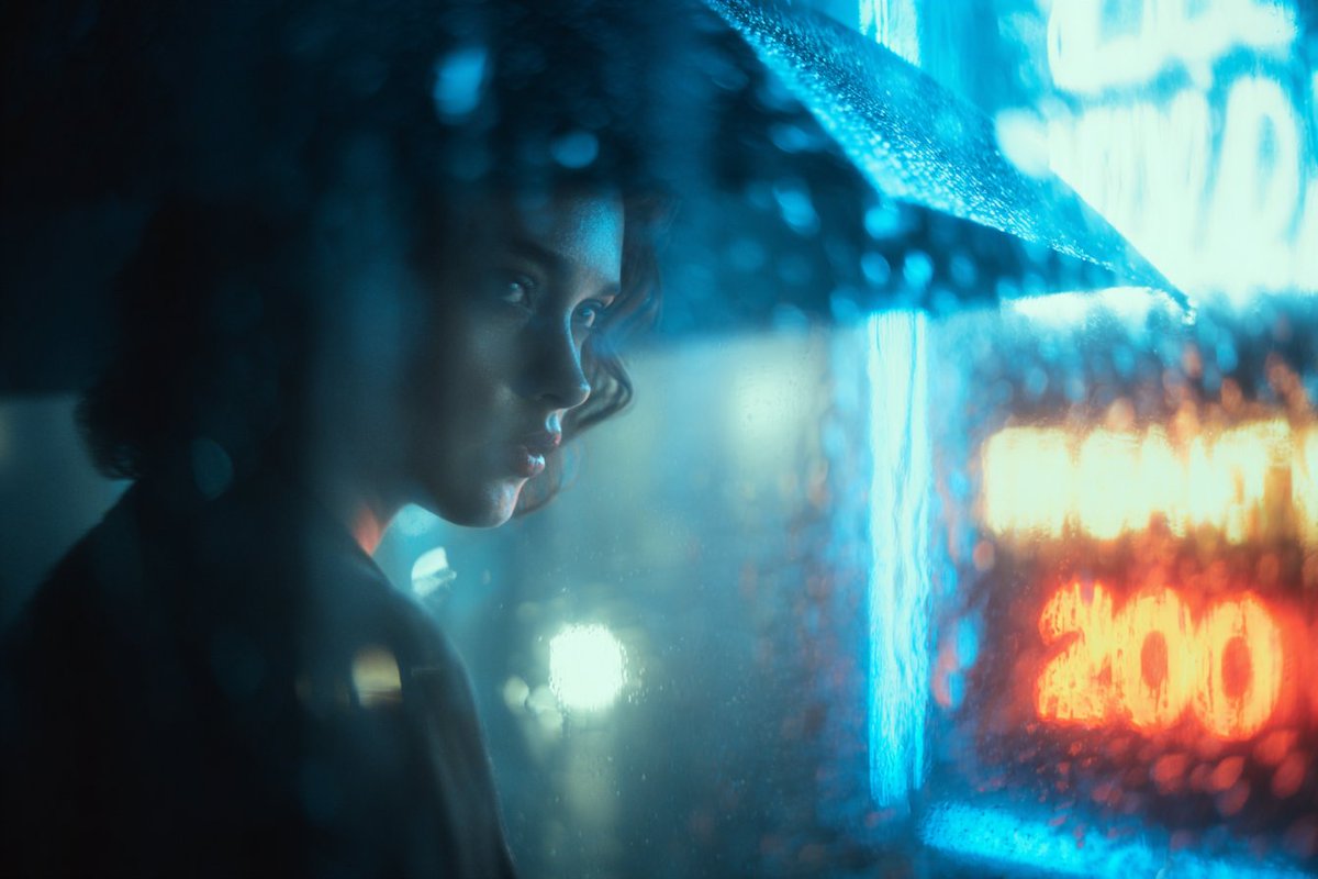 透过布满雨滴的玻璃看到的逼真[主体]。雾气弥漫的氛围，冷色调电影感光影，蓝光与钨丝灯光交织，伴有散景扭曲。情绪化且富有感染力，具备电影剧照的美学风格。 试试看，并分享你的作品 🔥