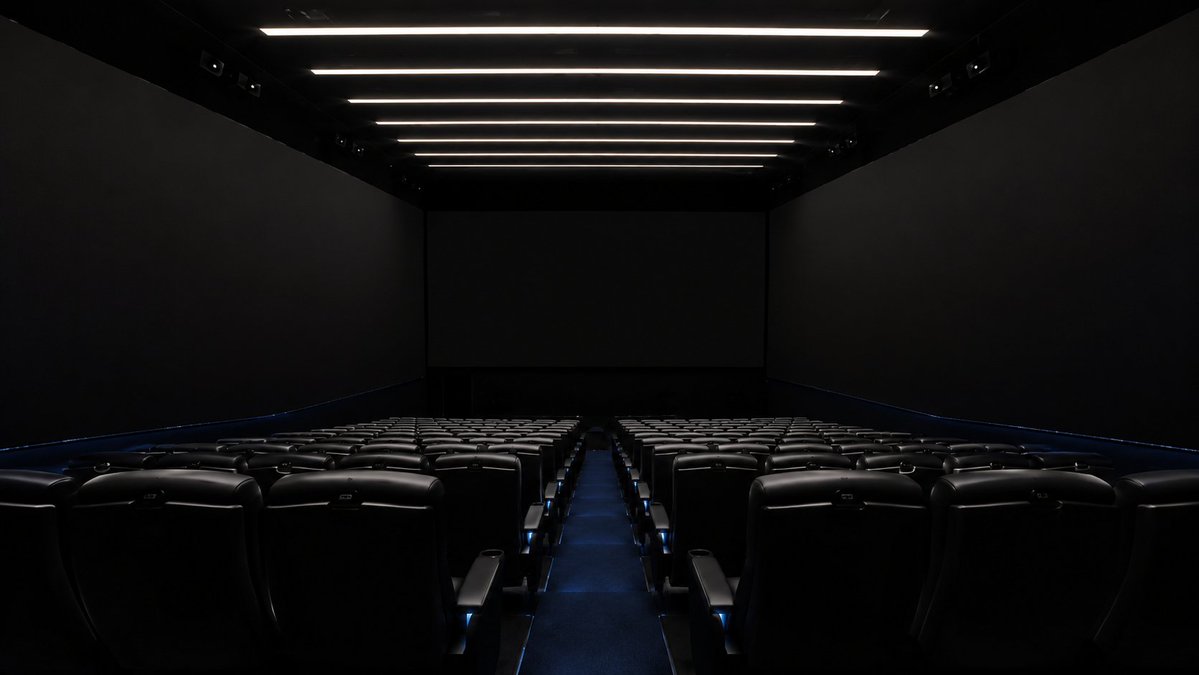 创建一个高度逼真的空电影院观众厅，紧密参考真实的 4DX with ScreenX 影厅外观，呈现现代商业影院的观感：中央前置银幕，投影画面延伸至左右两侧高耸的侧墙。使用从厅尾拍摄的对称广角视...