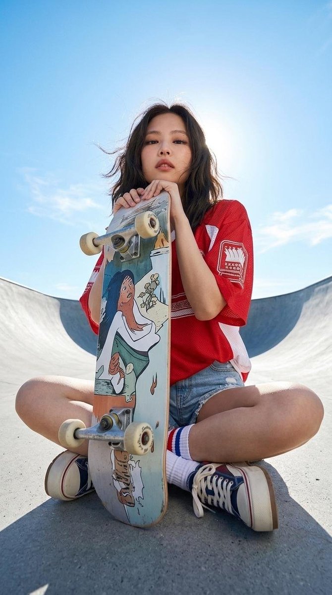 一位时尚年轻的东亚女性，神情自信冷酷，深色齐肩短发被微风轻轻吹拂。她身穿一件宽松的复古风格红色运动球衣，侧面带有白色拼接，胸前印有醒目的图形字母。下身搭配高腰浅色水洗牛仔短裤，带有强烈的做旧处...