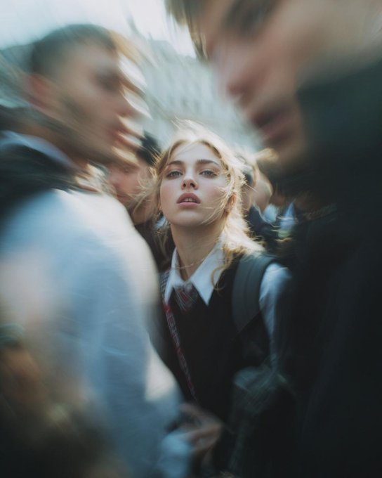狗仔队风格的极近景特写照片，一位面部特征鲜明的女性，在毫无防备时猛然转向镜头。仅拍摄面部与肩膀，采用低角度仰拍。强烈的硬光直闪，高ISO颗粒感，原始抓拍的街头摄影质感。背景是人群拥挤的场景，带...