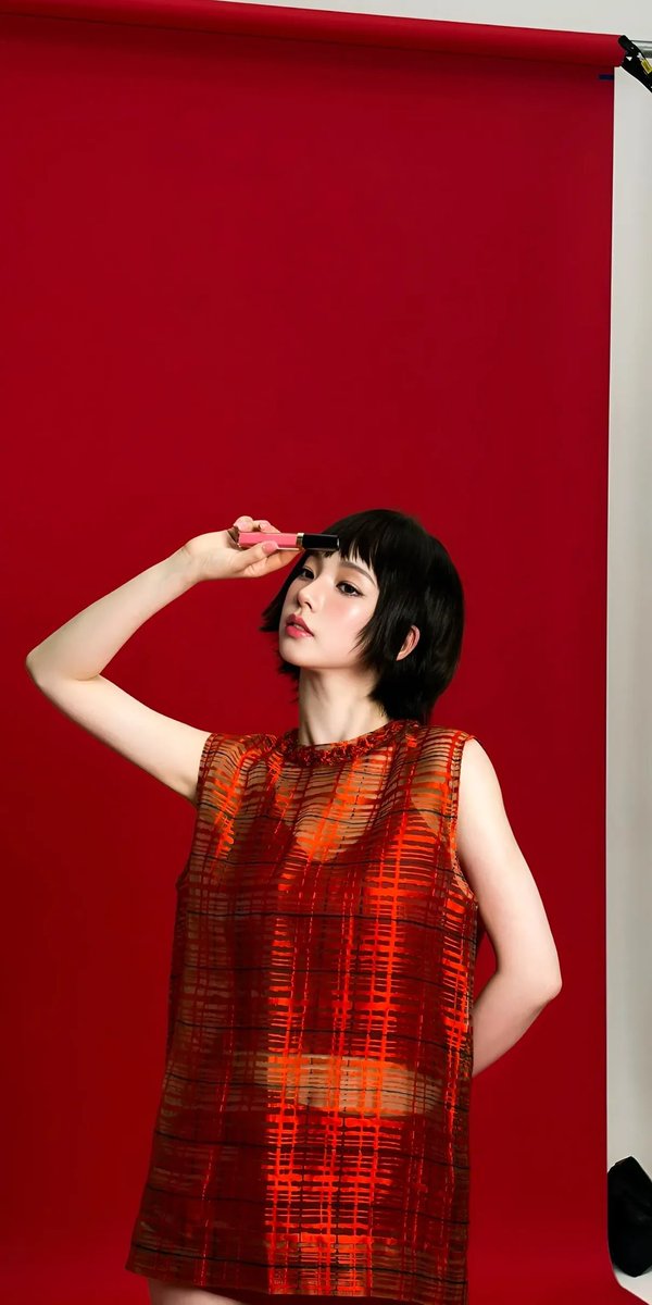 高端时尚编辑大片美妆广告,画面中是一位优雅的东亚女性模特,拥有无瑕瓷器般肌肤、水润自然的双唇、柔和的蜜桃色腮红以及细腻的微翘眼线。利落短款黑色波波头发型,搭配轻盈碎刘海。她身穿一件半透明金属质...