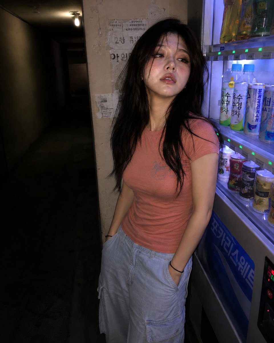 一张超写实的 4K 抓拍照，照片中是一位年轻东亚女性，夜晚站在昏暗走廊里一台发出轻柔嗡鸣的自动售货机旁。苍白的皮肤反射着直接打来的相机闪光灯，并混入自动售货机投出的微弱霓虹光。她留着自然凌乱、...