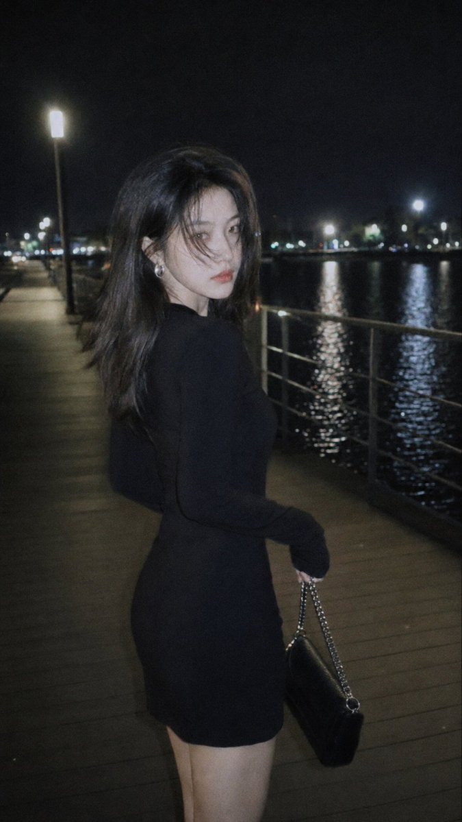 风格：CCD 柔光胶片摄影 概念：情绪感城市夜景街头人像 场景：夜晚的湖边栈道，街灯光芒，水面反光，栏杆步道 着装：修身黑色长袖连衣裙，银色耳饰，小型链条包 氛围：冷酷疏离，深夜氛围，克制优雅...