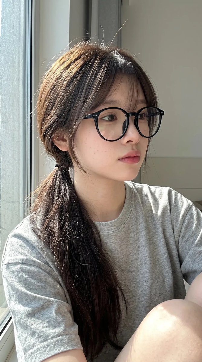 超写实抓拍式智能手机自拍照肖像：一位年轻东亚女性室内坐在一扇大窗户旁，处于明亮的自然日光下。保持与上传的面部参考高度相似的面部特征：柔和的椭圆形脸型、纤细的下颌线、自然偏窄的鼻梁、轮廓轻柔的嘴...