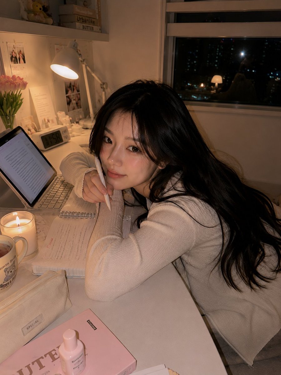 超写实的温馨韩国书房人像：一位美丽的韩国女性夜晚随意地坐在白色书桌上，旁边放着她的笔记本电脑，双膝轻柔地蜷向身体，上半身转向镜头，露出温柔害羞的微笑。身穿柔软的米色一字肩休闲上衣，搭配宽松舒适...
