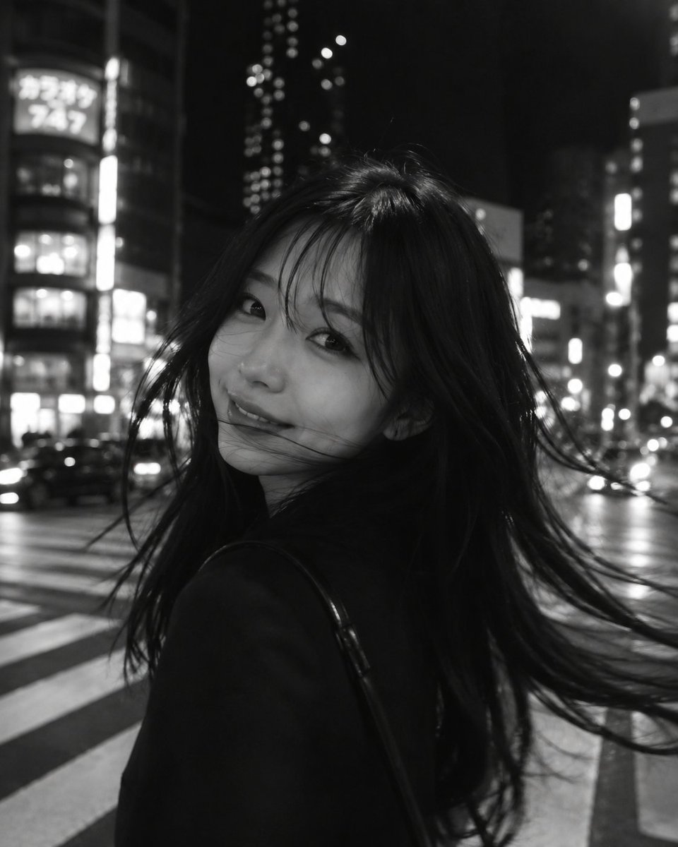 一张黑白电影感的城市夜景摄影作品，采用长曝光与刻意营造的运动模糊。画面前景中是一位年轻女子，略微偏离中心，正在转身的瞬间，她的长发以柔和、如幽灵...
