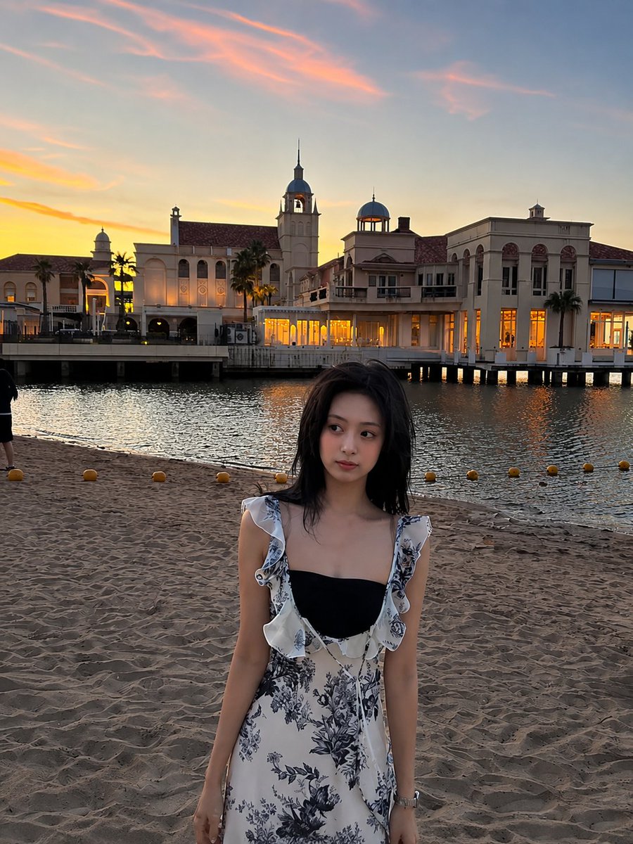超现实电影感旅行照片：一位年轻的东亚女性站在沙滩上，沐浴在令人屏息的日落中，采用竖向 3:4 构图。她身穿一件精致的白色连衣裙，点缀着细腻的蓝色花卉印花，肩带为荷叶边设计，整体剪裁贴合身形。她...