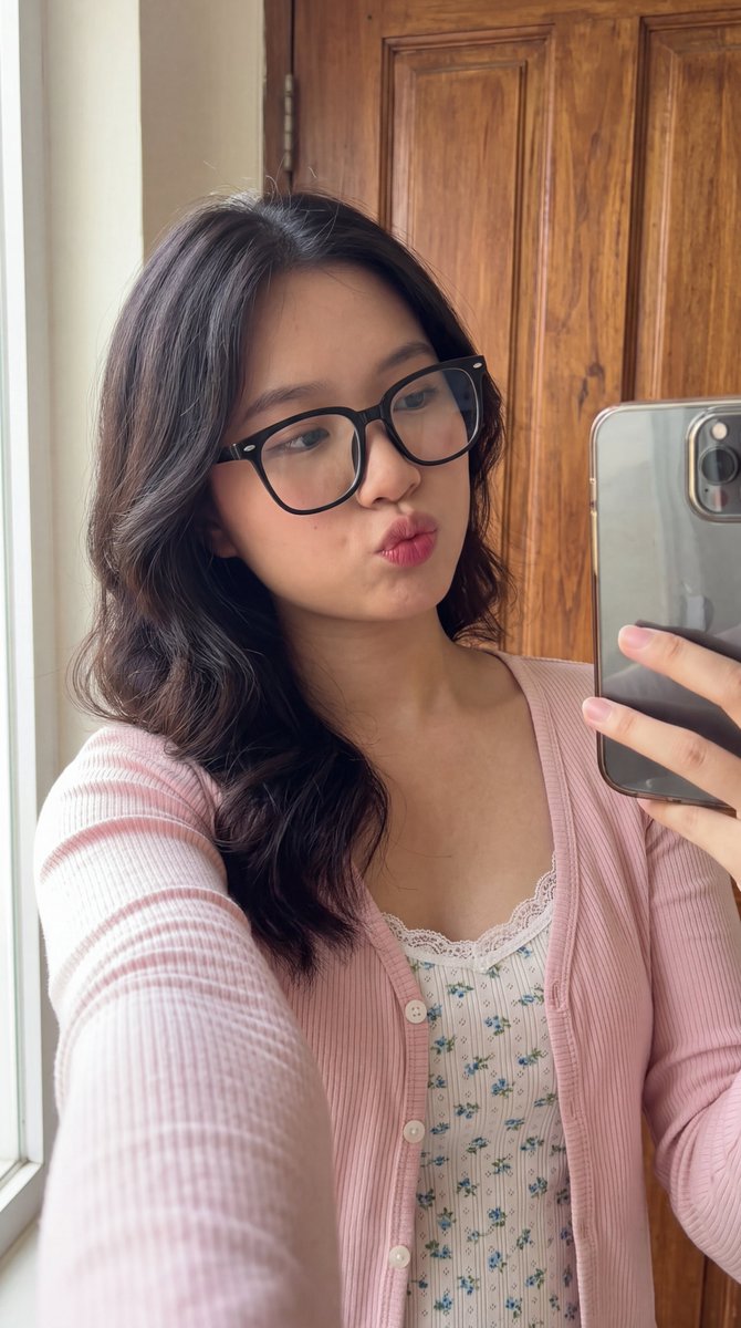 [Higgsfield 营销工作室图像提示] ar 9:16 4K High 一位年轻东亚女性的近距离自拍肖像，长长的波浪状深棕色头发垂落在一边肩膀上。她戴着一副大号黑框眼镜，俏皮地撅起嘴唇做...