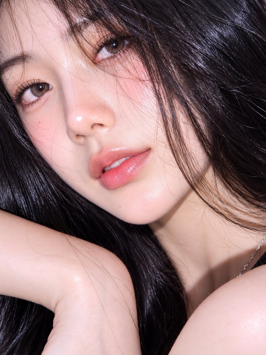 超逼真、令人无法抗拒的抢眼抓拍肖像照：一位魅力十足的年轻女子侧身躺在浓郁的青绿色（绿松石蓝）表面上，以亲密的特写角度拍摄，构图略微倾斜。她一头如丝般顺滑的乌黑长发自然地在她头部周围散开，缕缕飞...