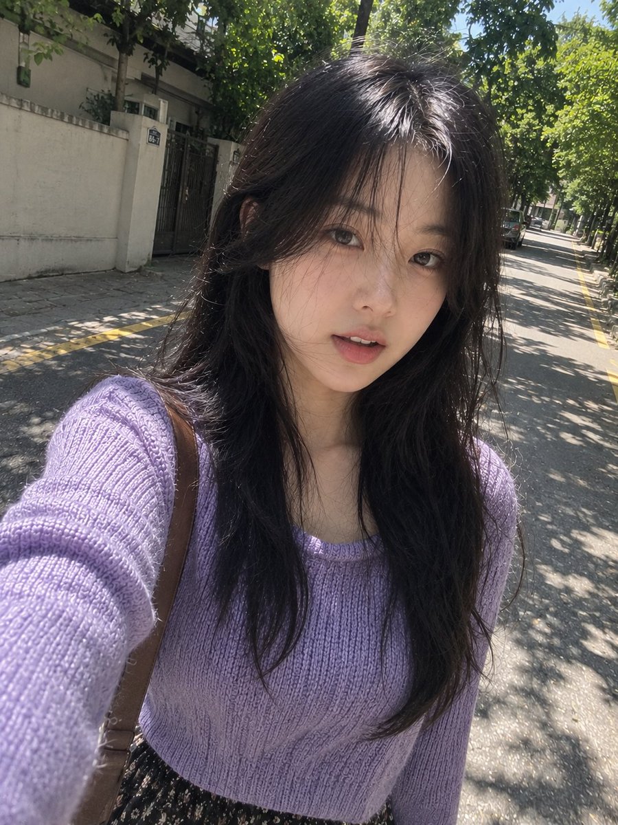 一张完全自然、照片写实风格的智能手机自拍照，画面中是一位年轻的东亚女性在一条安静的林荫街道上随意行走时拍摄，看起来就像是她自己一边走路一边用手机...
