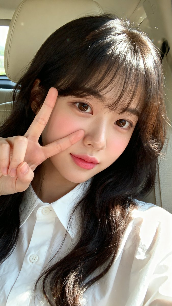 [Seedream 4.0 Prompt] ar 9:16 High 一张年轻东亚女性（韩国外貌）的特写自拍肖像，皮肤白皙光滑，五官柔和自然。她留着长长的、略带波浪的深棕至黑色头发，柔软的刘海...