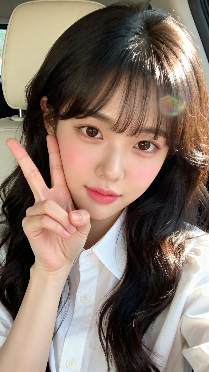 [Seedream 4.0 Prompt] ar 9:16 High 一张年轻东亚女性（韩国外貌）的特写自拍肖像，皮肤白皙光滑，五官柔和自然。她留着长长的、略带波浪的深棕至黑色头发，柔软的刘海...