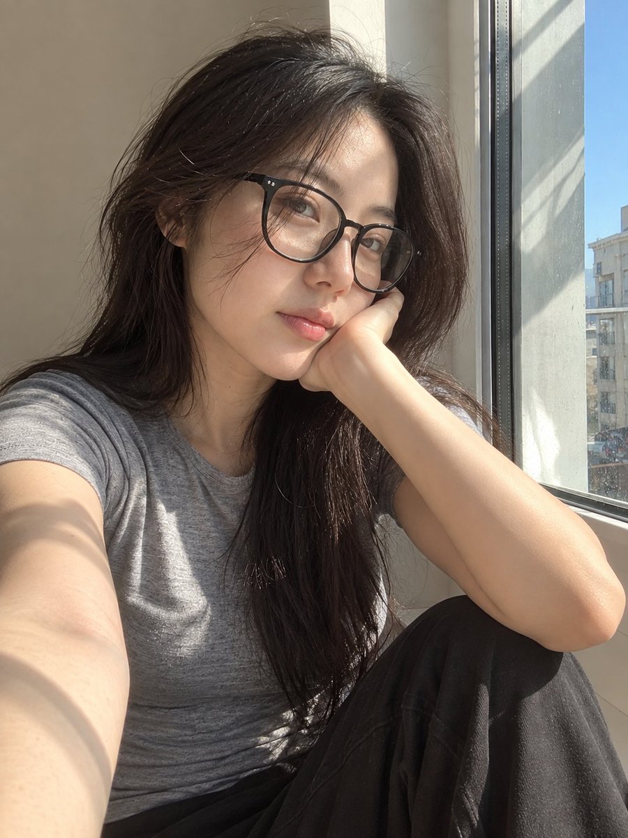 超写实风格的休闲智能手机自拍照：一位年轻东亚女性坐在安静房间内靠近阳光照射的窗户旁。保持与面部参考的高度相似性，包括柔和轮廓的鹅蛋脸、温和的下颌线、自然比例的鼻子、真实的唇形、均衡的眼距、微妙...