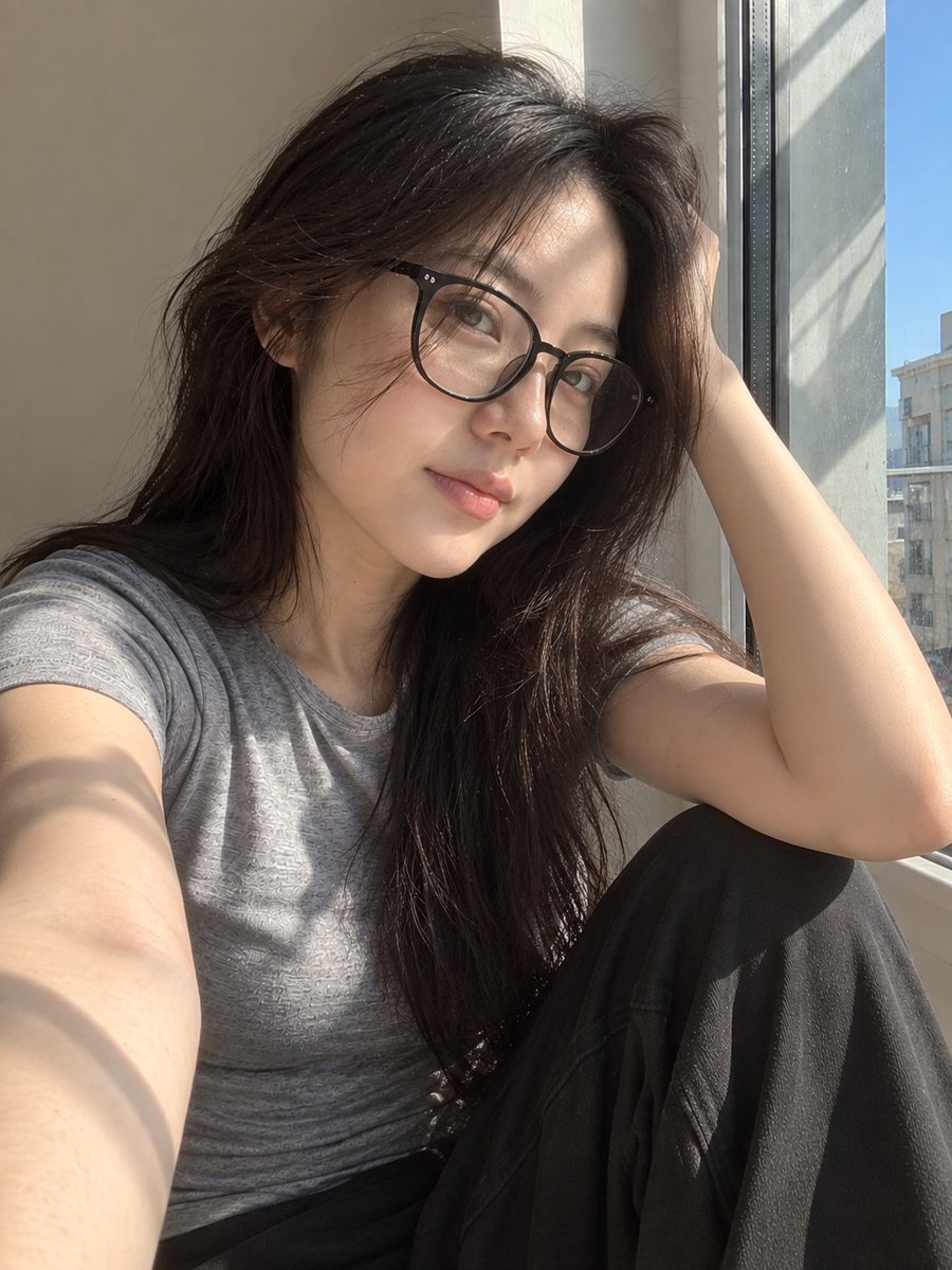 超写实风格的休闲智能手机自拍照：一位年轻东亚女性坐在安静房间内靠近阳光照射的窗户旁。保持与面部参考的高度相似性，包括柔和轮廓的鹅蛋脸、温和的下颌线、自然比例的鼻子、真实的唇形、均衡的眼距、微妙...